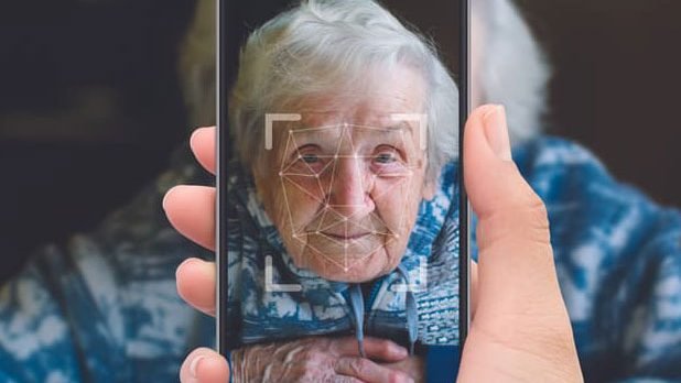 a person holding a phone up in front of an elderly person, whose face is visible on the screen